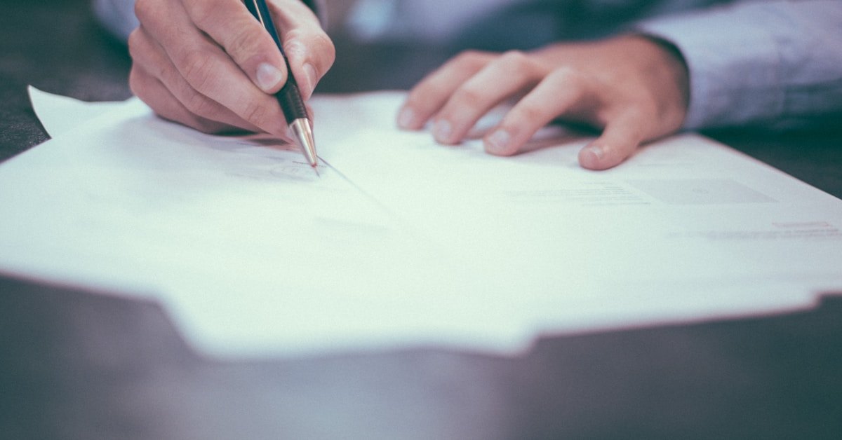 Personne remplissant un formulaire papier à la main, stylo en main