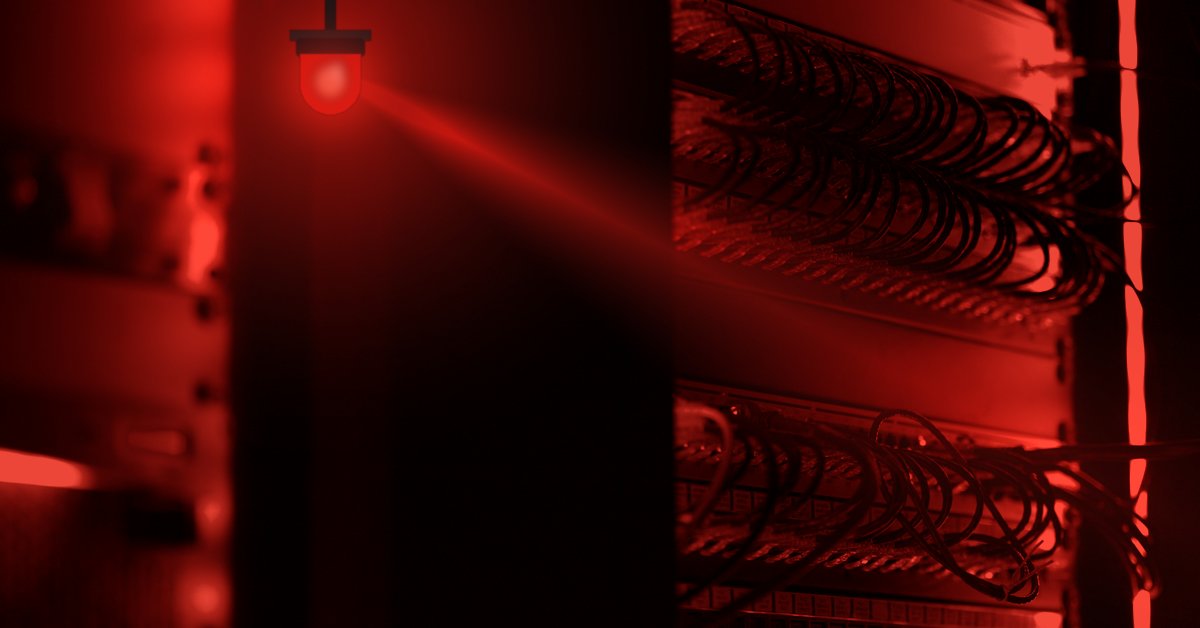 A server room bathed in red light, with a warning beacon flashing above the racks
